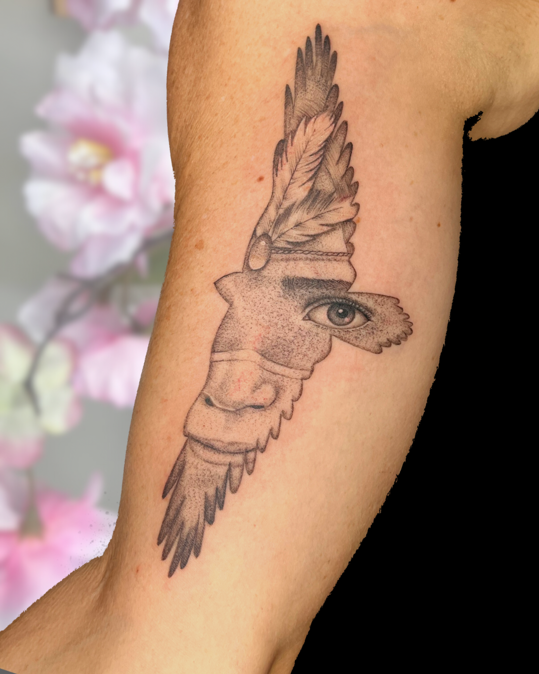 Black and grey surreal bird with eye on bicep