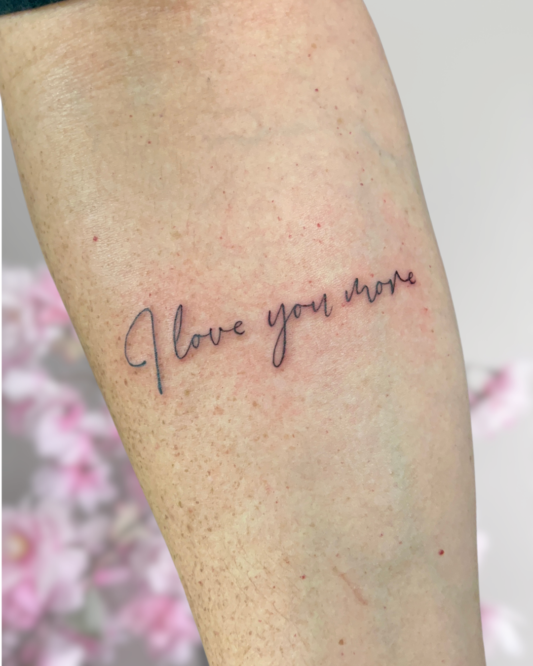 Fine line script 'I love you more' on forearm