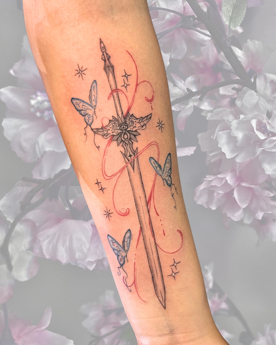 Fine line ornamental sword with butterflies and red ribbon on forearm