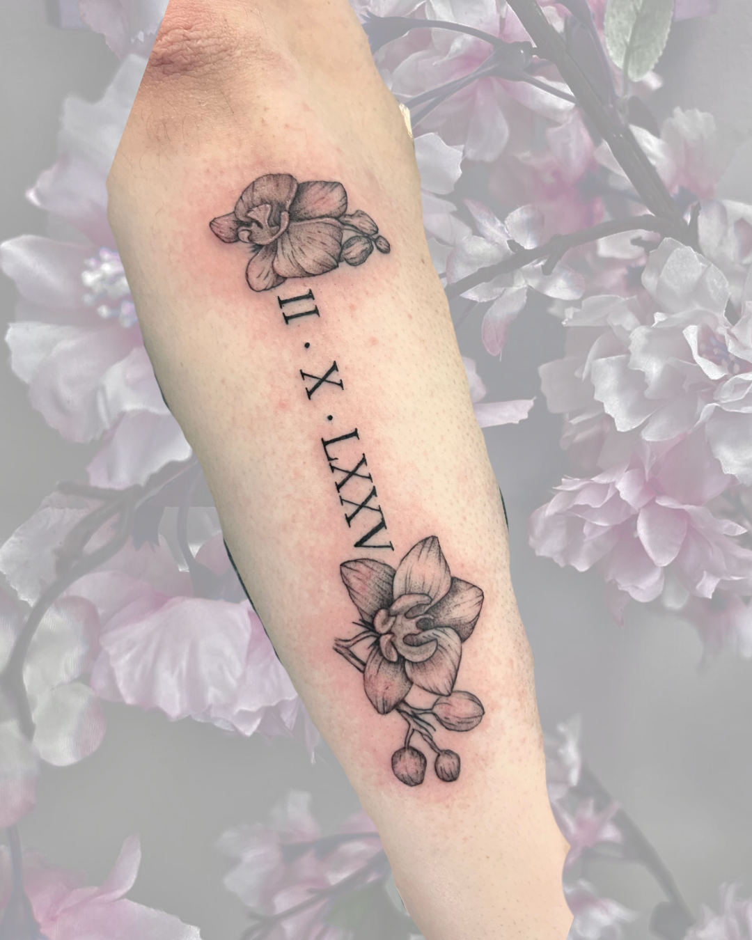 Fine line orchids with Roman numerals on forearm
